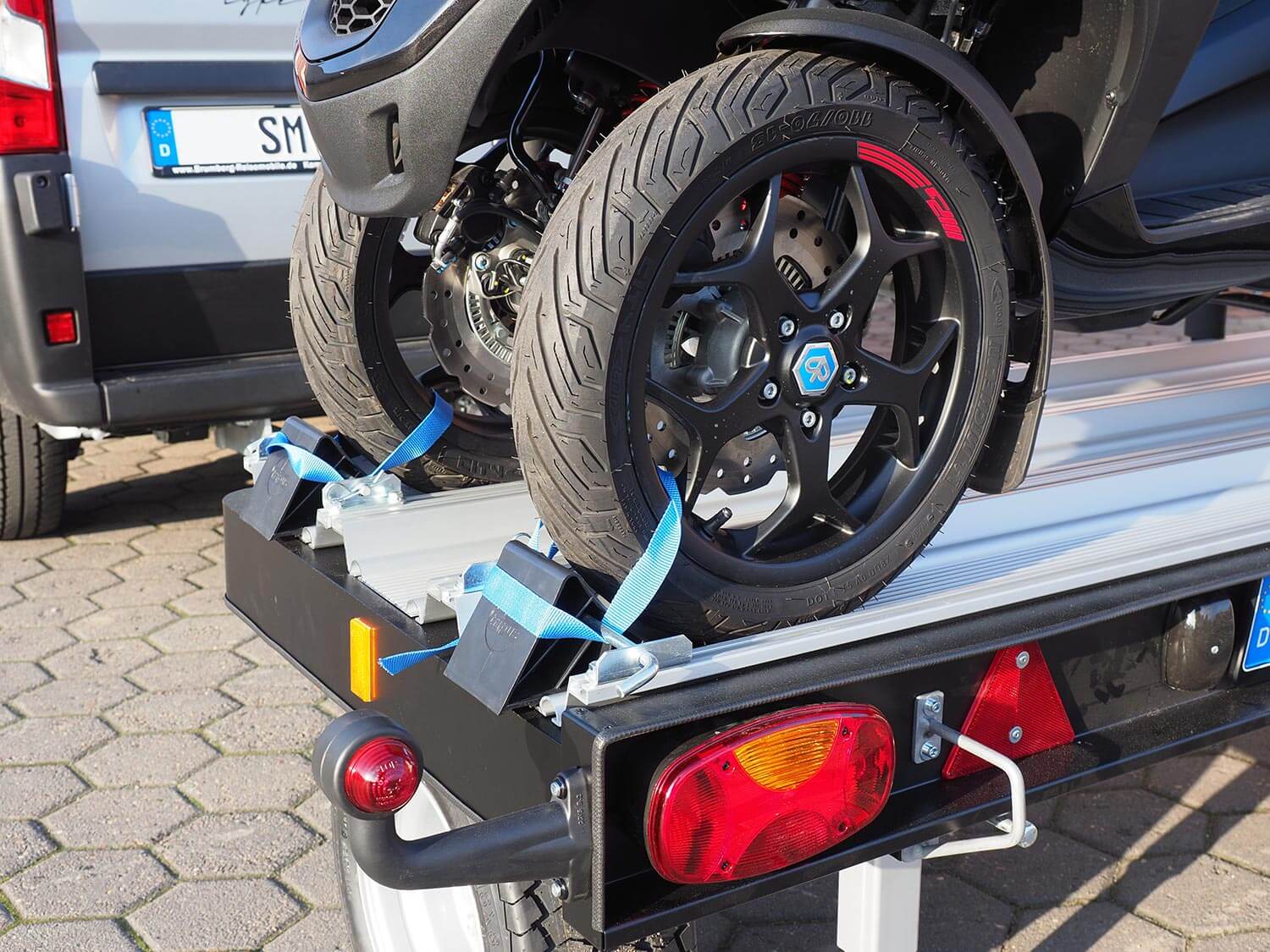 Die Vorderräder eines MP3 Rollers sind auf dem SMV Alu-Star Rolli MP3 mit Gurten und Keilen befestigt.