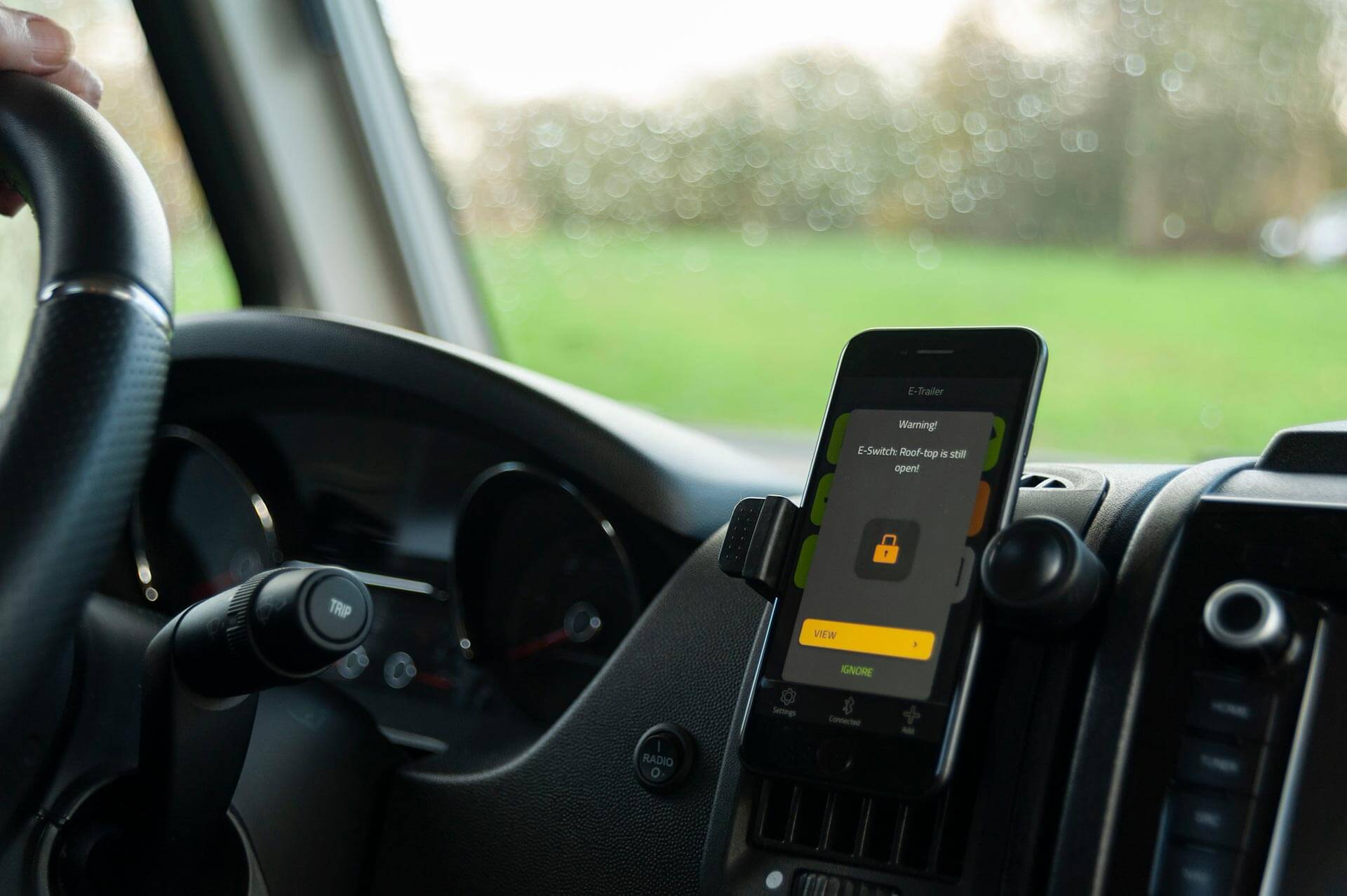 Im Cockpit eines Wohnmobils Smartphone mit E-Switch Warnmeldung.