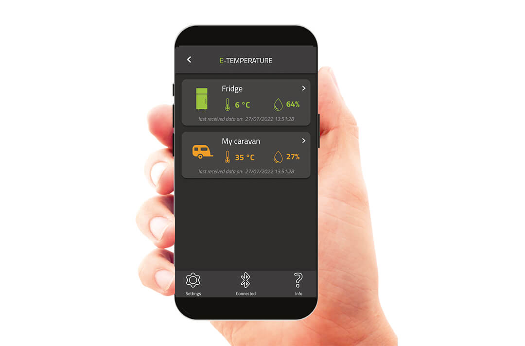 Hand hält Smartphone und zeigt in der E-Temperature App eine Übersicht über die Temperatur im Innenraum und im Kühlschrank.