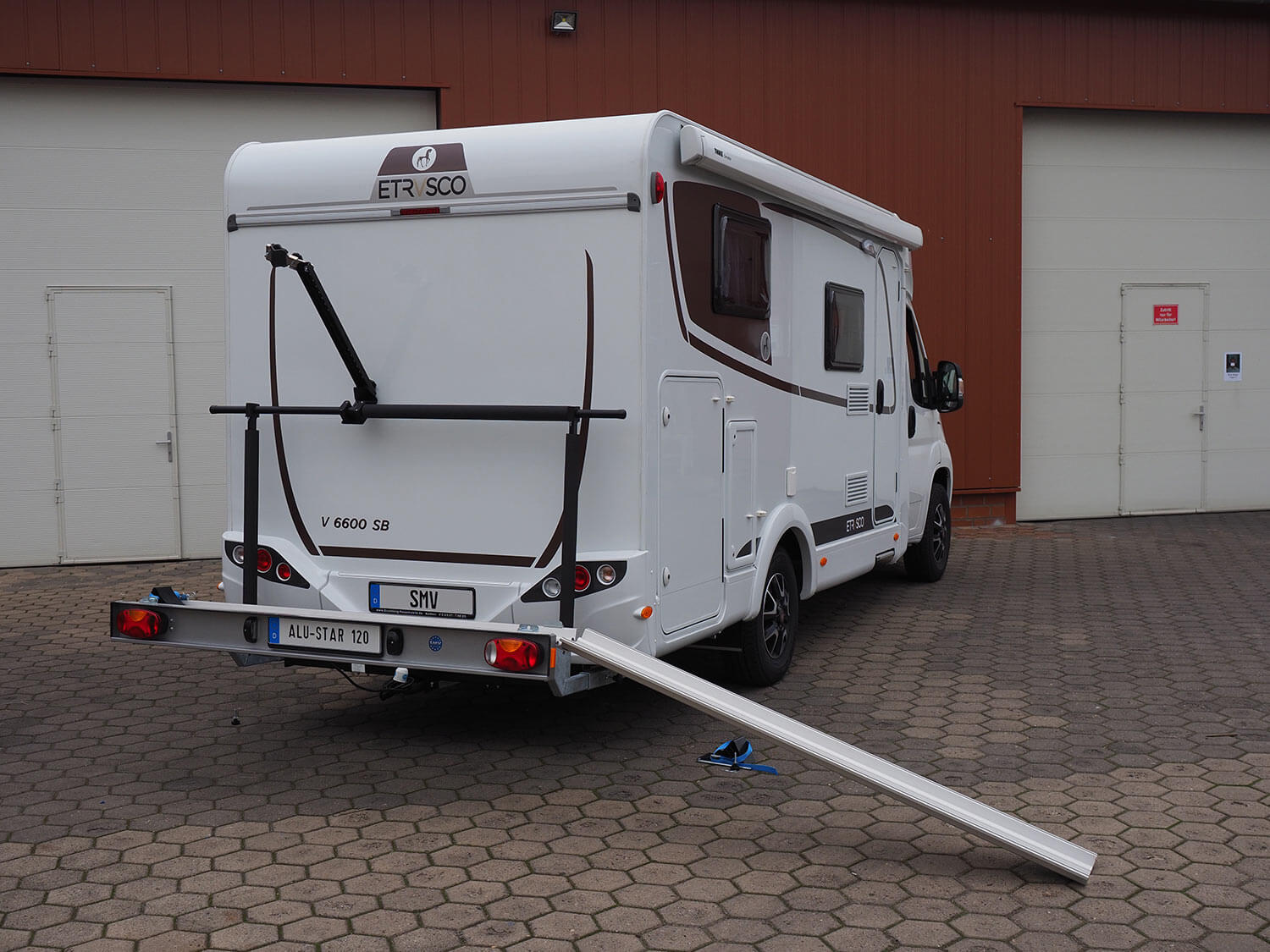 SMV Alu-Star 120 montiert an Wohnmobil. Heckansicht mit angebauter Auffahrrampe.