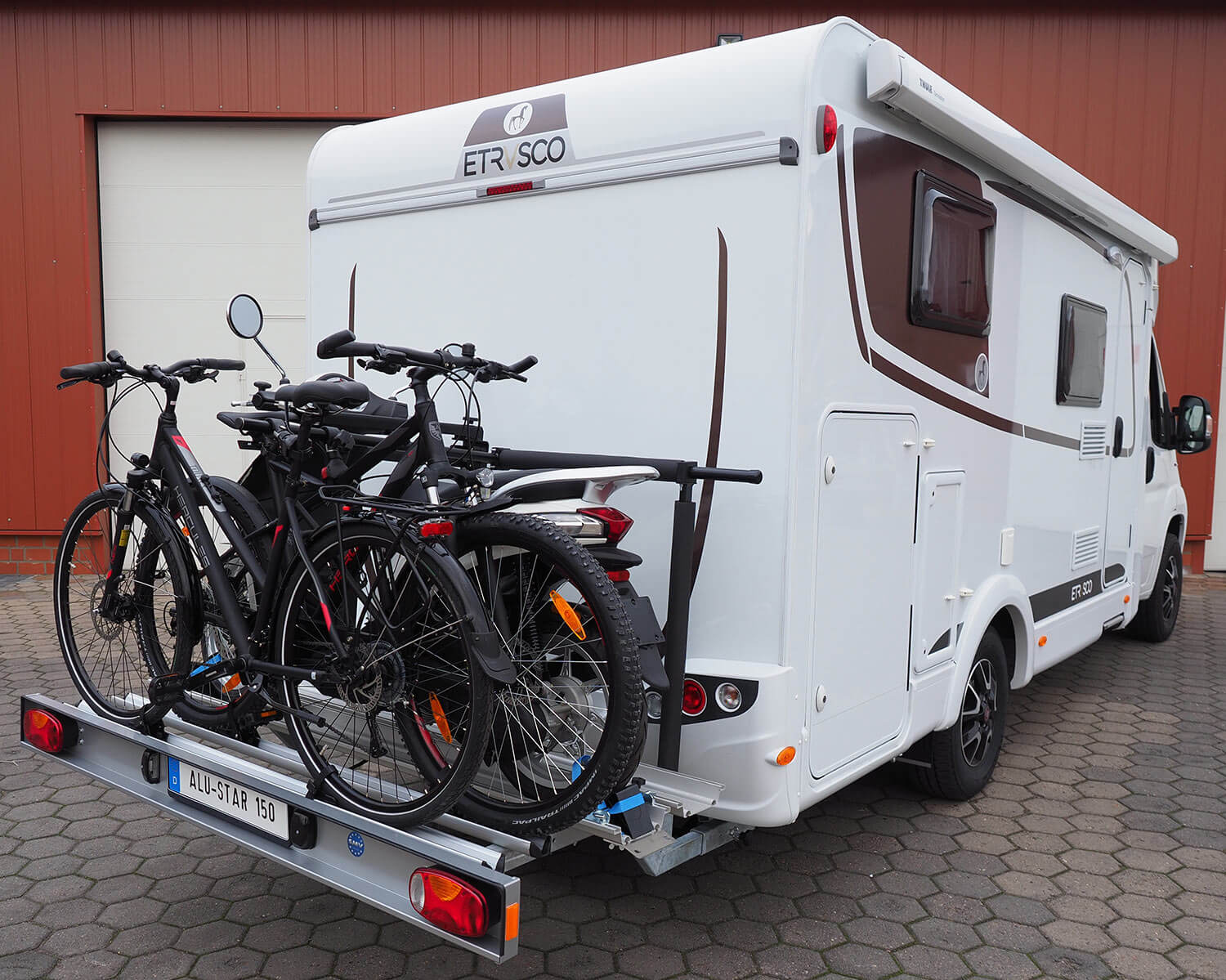 SMV Alu-Star 150 an Wohnmobilheck mit einem Roller und Fahrrädern beladen.