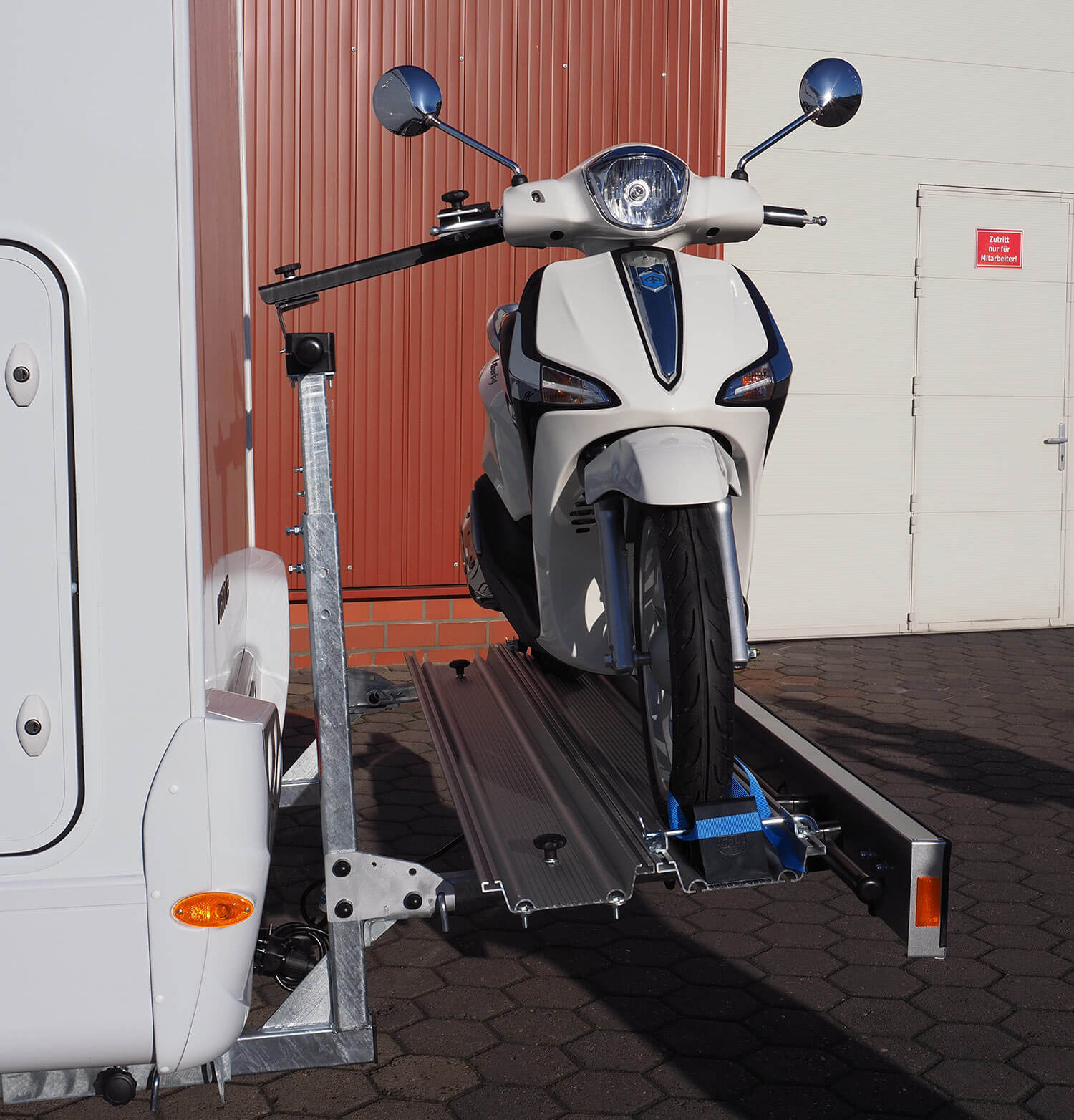 Seitenansicht SMV Rad Max 130, beladen mit einem Roller, der mit Haltearm, Keil und Riemchen befestigt ist.